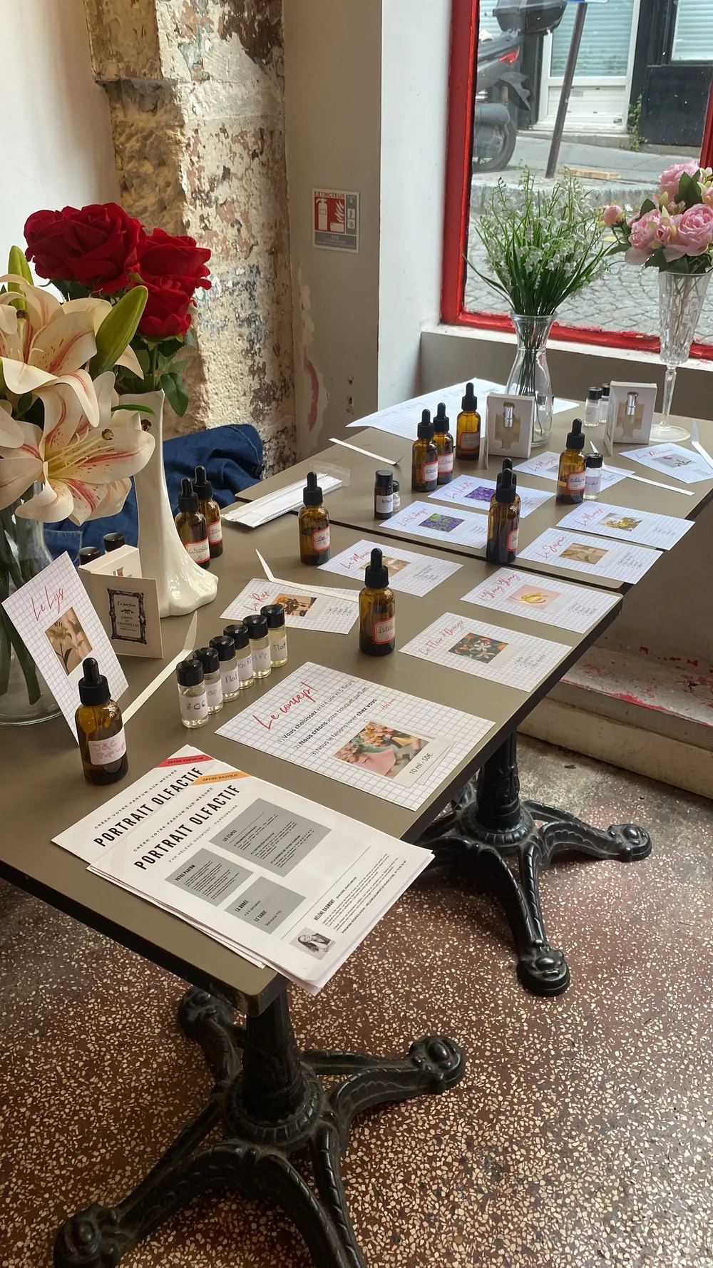 Grande table d'atelier dressée avec flacons, fiches et fleurs